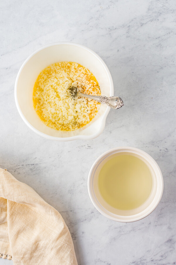 Whisking the eggs, egg yolk, and cheeses in a bowl. Pasta water on the side.