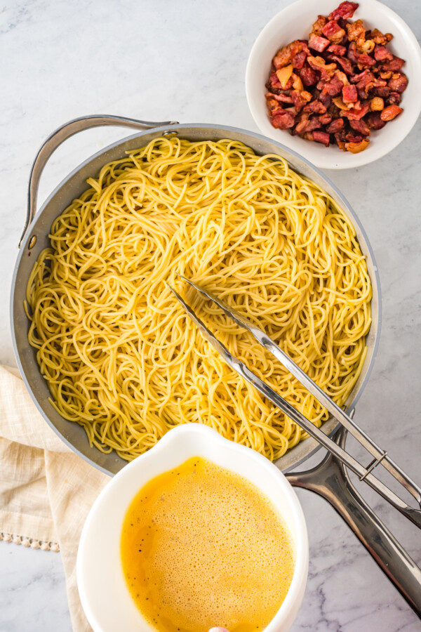 Spaghetti in a pan with tongs. 