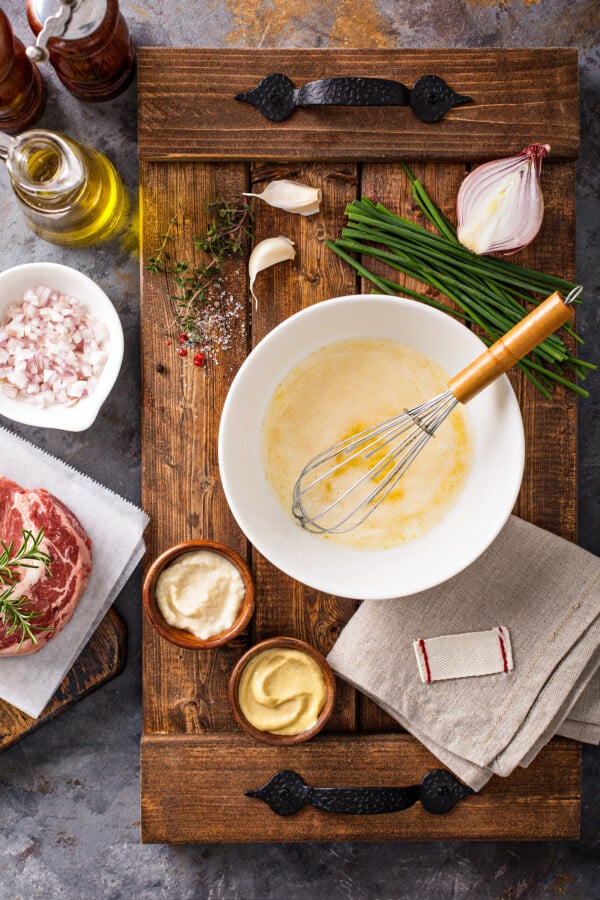 Ingredients in bowls on a cutting board with a steak next to it.