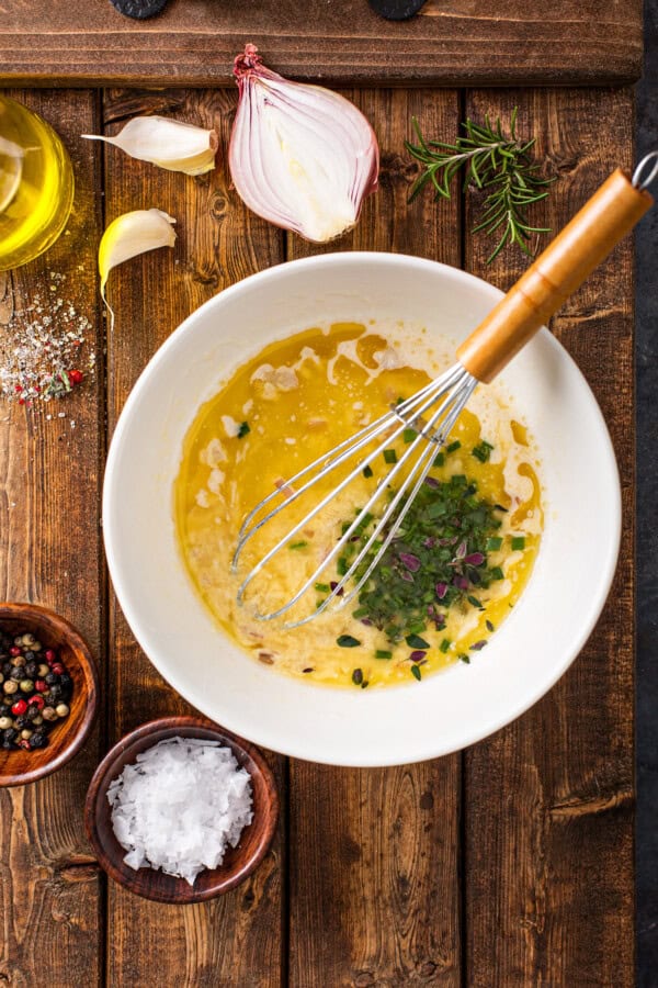 A bowl with butter and herbs being whisked together.