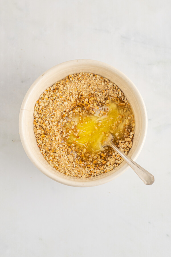 Mixing melted butter into crumbs.