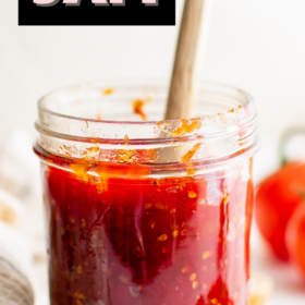 Tomato jam in a jar with a wooden spoon and tomato jam on toast with basil on top.