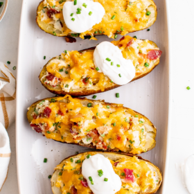 Twice baked potatoes lined up on a serving plate.