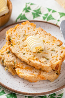Two jalapeño beer bread slices with a knob of butter on top.