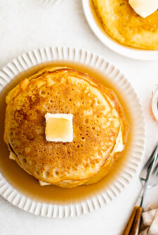 Overhead shot of a stack of johnny cakes, topped with butter and syrup.