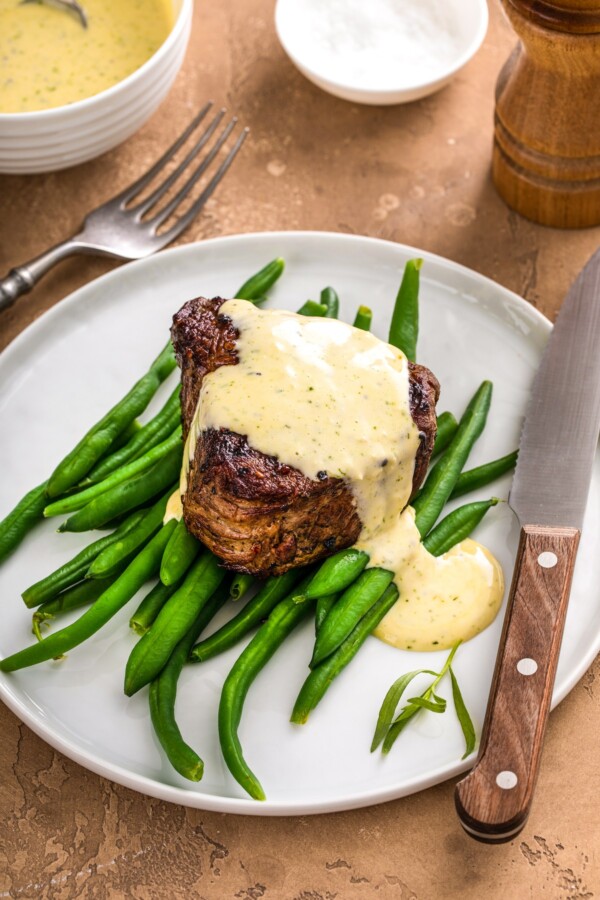 Béarnaise Sauce on a steak with a fork and steak knife.