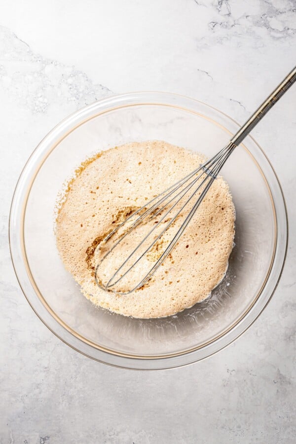 Yeast proofing in a glass bowl with a whisk.