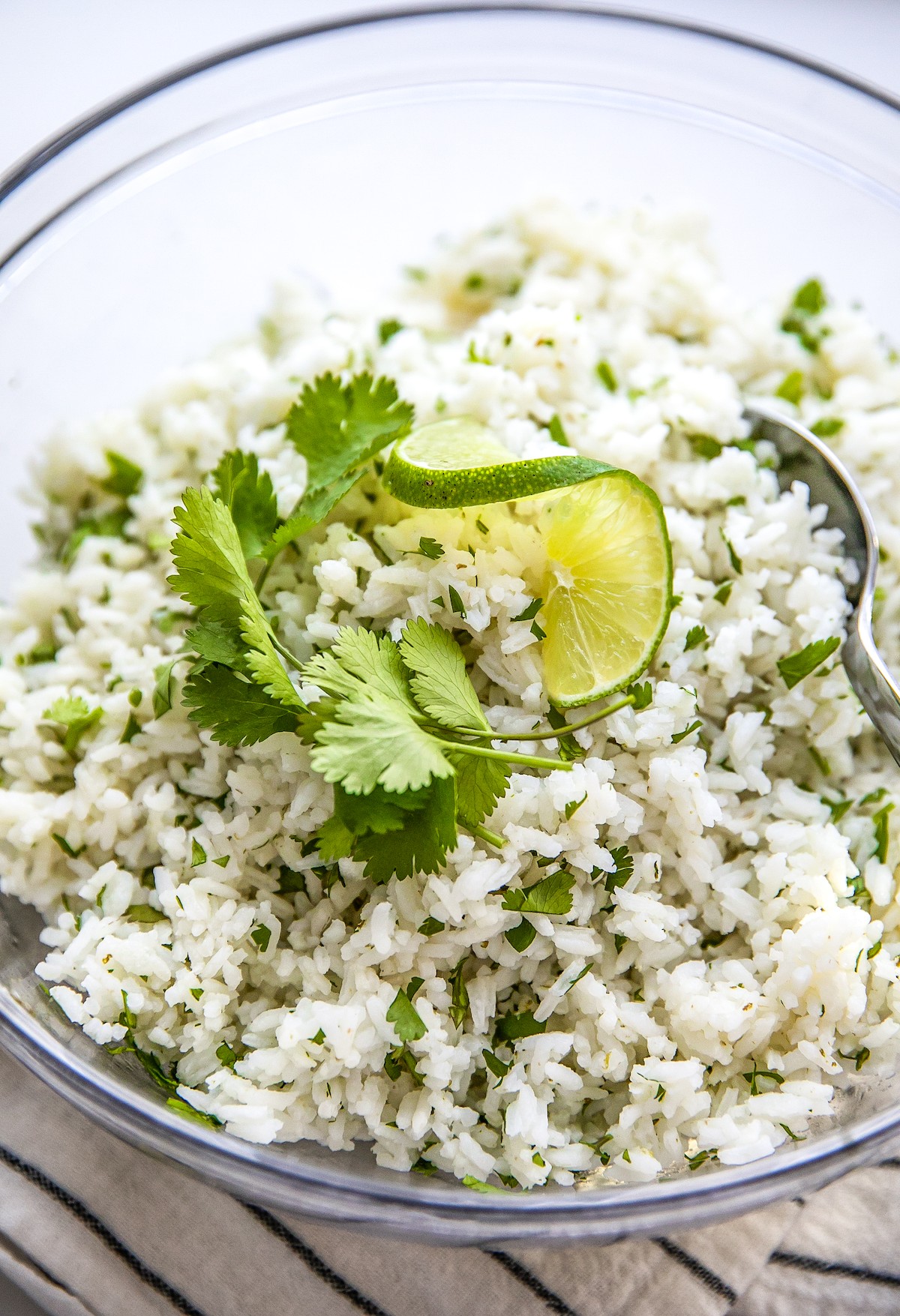 Cilantro lime rice with cilantro and a lime wedge on top.