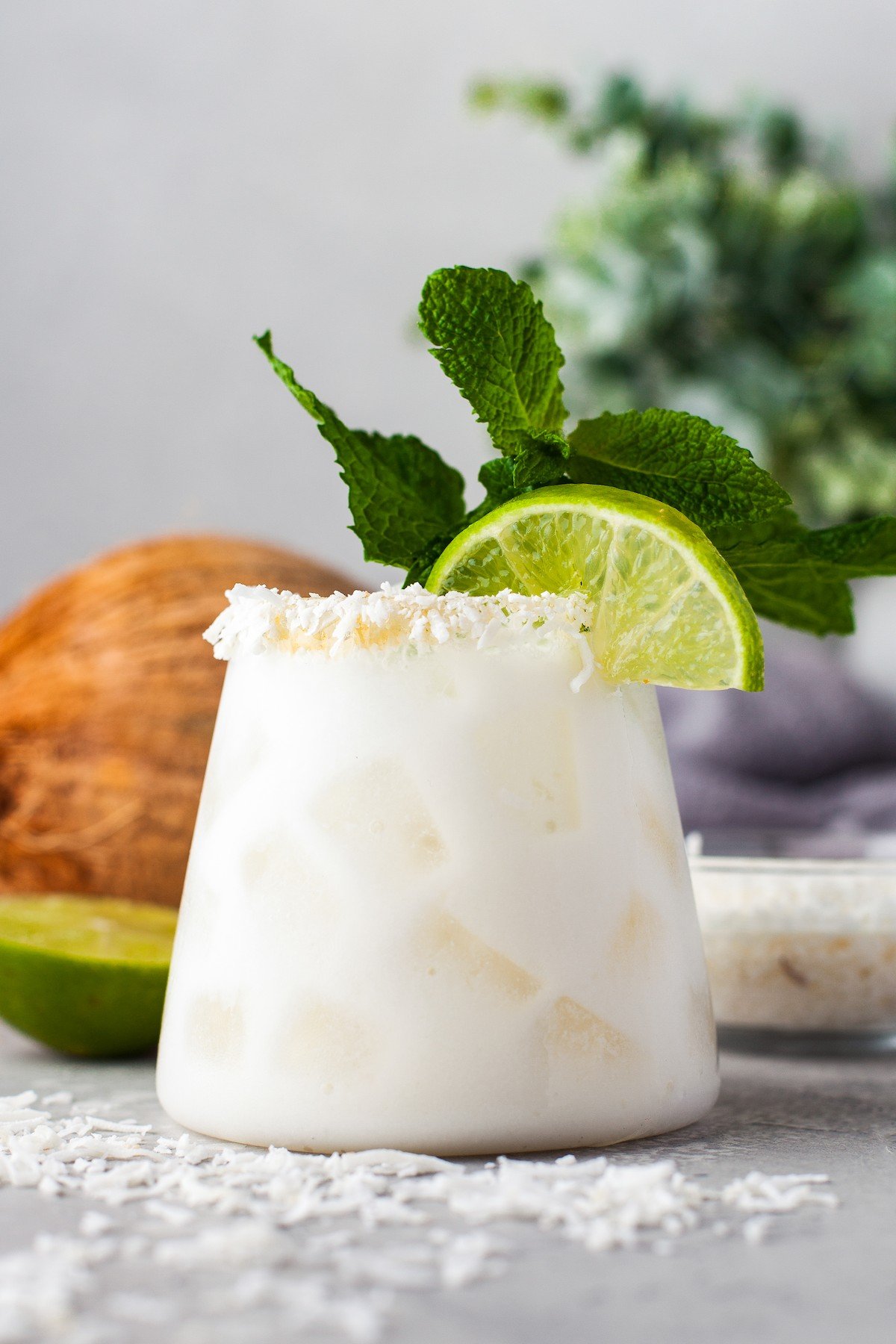 A coconut margarita with a coconut rim and a lime wedge. 