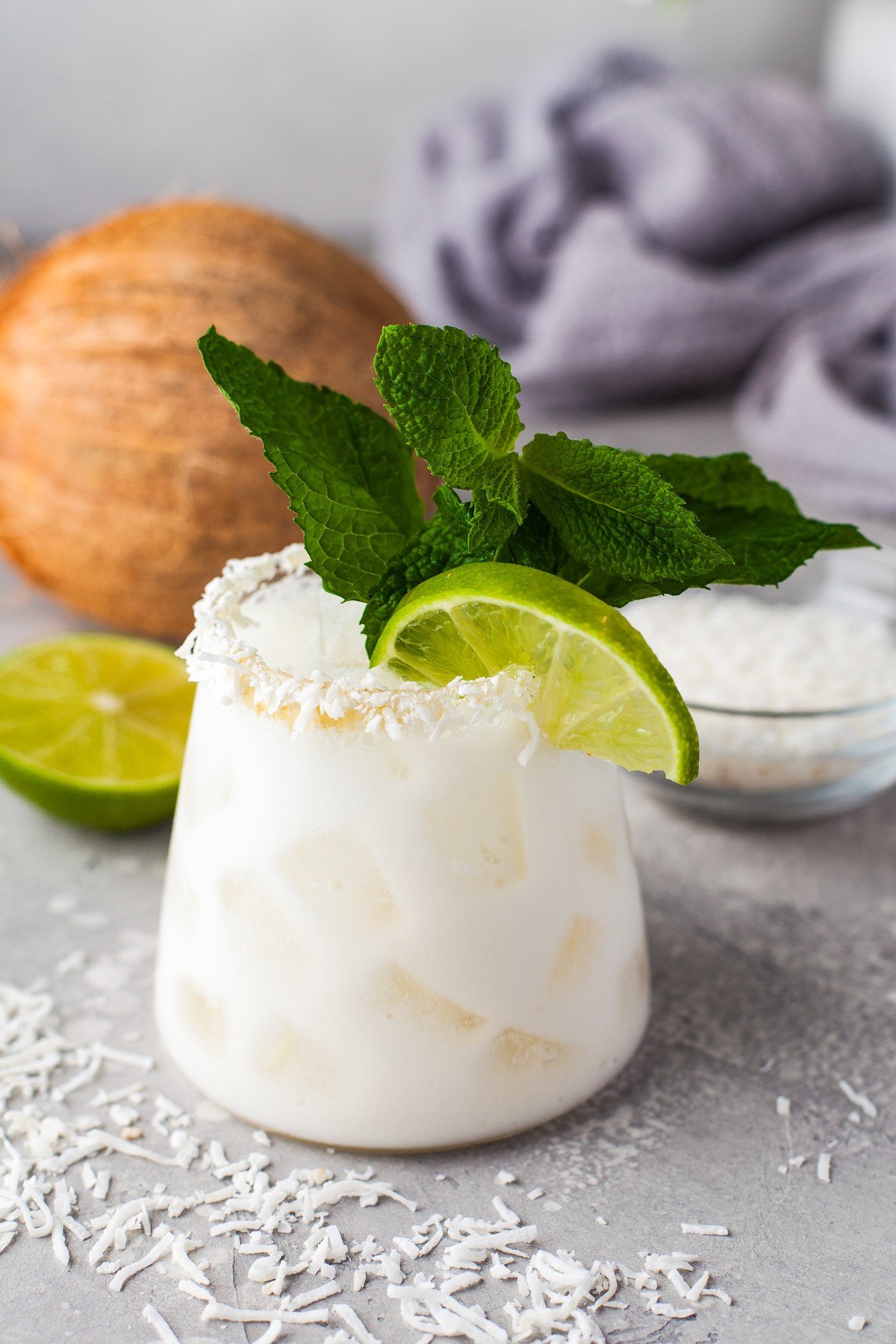 Angled shot of coconut margarita with a fresh mint and a lime wedge. 