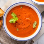 A bowl of Copycat Panera Tomato Soup with a grilled cheese on the side.
