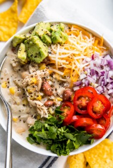 A large bowl of white chili, topped with avocado, tomato, red onion, and more.