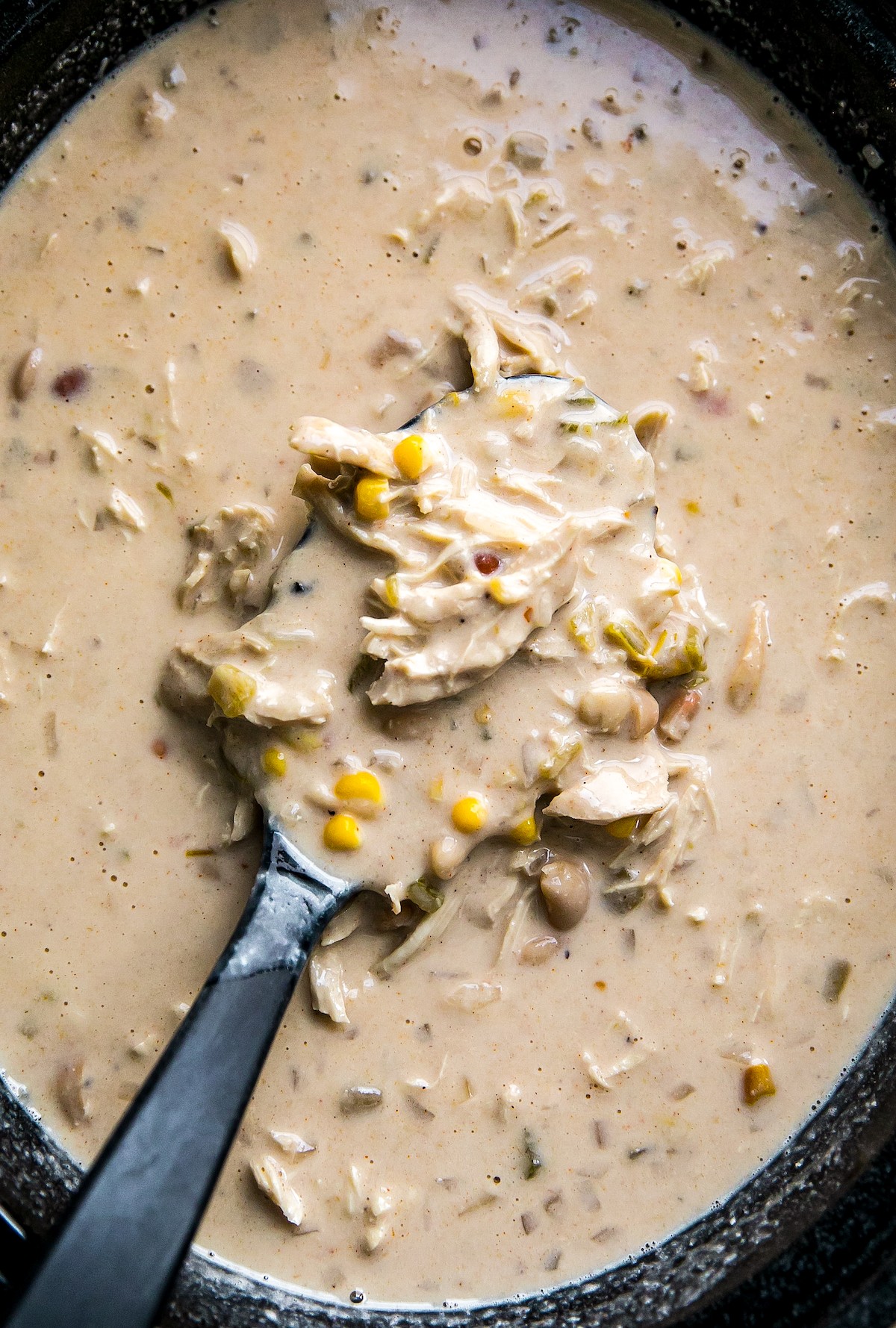Slow cooker white chicken chili in a crockpot with a ladle.