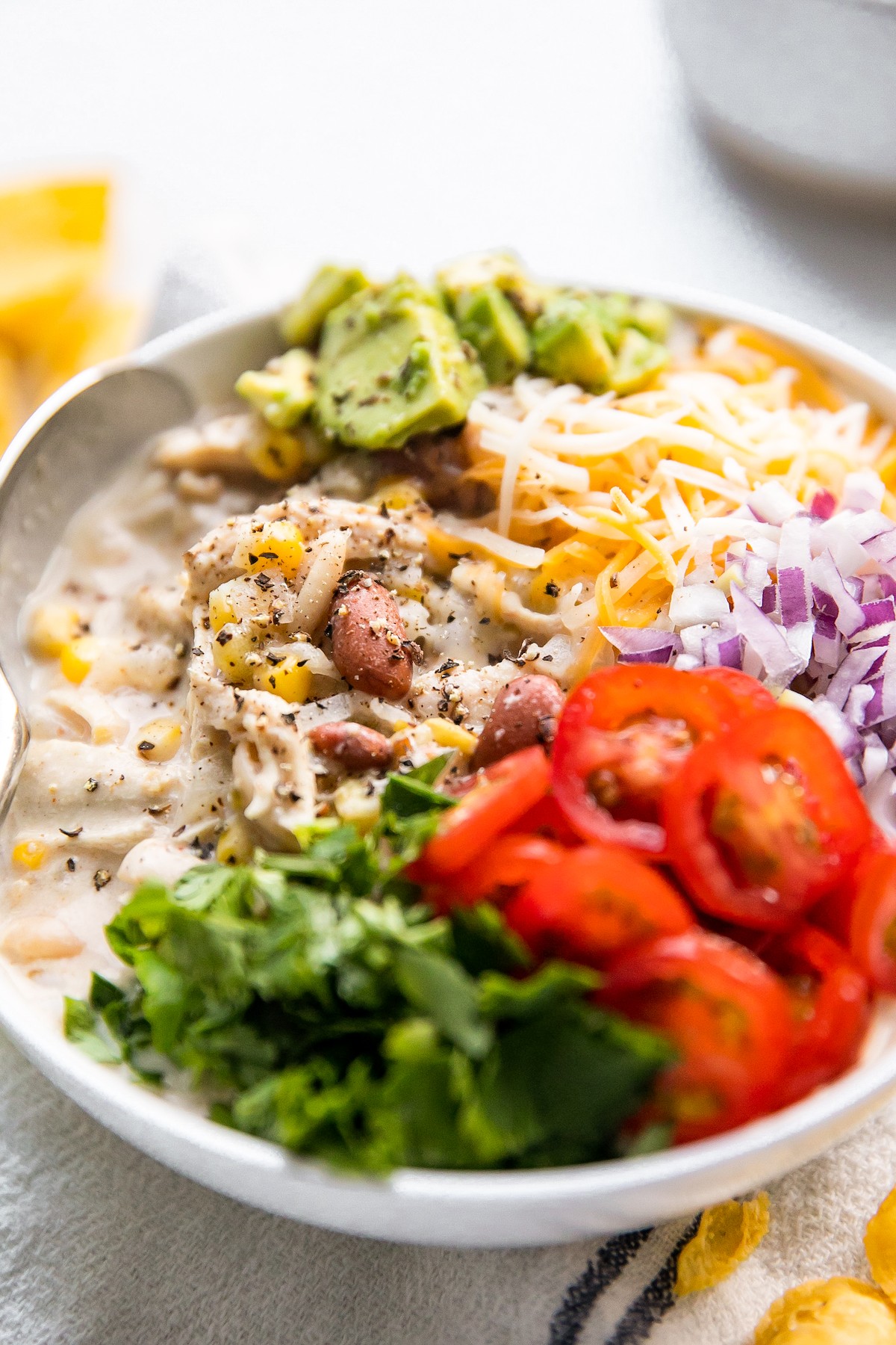 Slow cooker white chicken chili with colorful toppings arranged in the bowl.