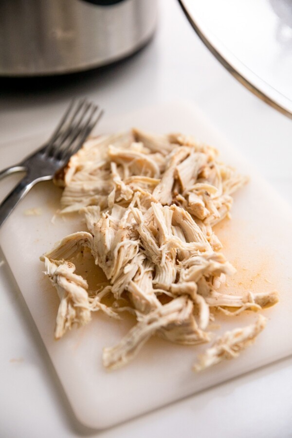 Shredded chicken on a cutting board with two forks.