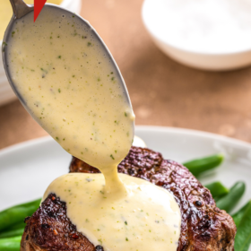 Béarnaise Sauce in a bowl and being poured over a steak.