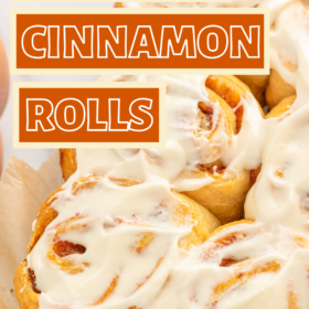 Pumpkin cinnamon rolls on parchment paper with cinnamon icing on top.