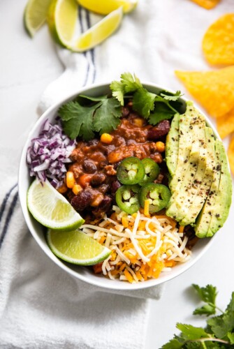 A bowl of beef chili topped with avocado, jalapeno, and more.