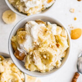 Servings of banana pudding in small bowls with wooden-handled spoons.