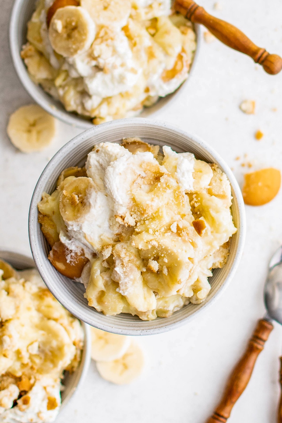 Servings of banana pudding in small bowls with wooden-handled spoons.
