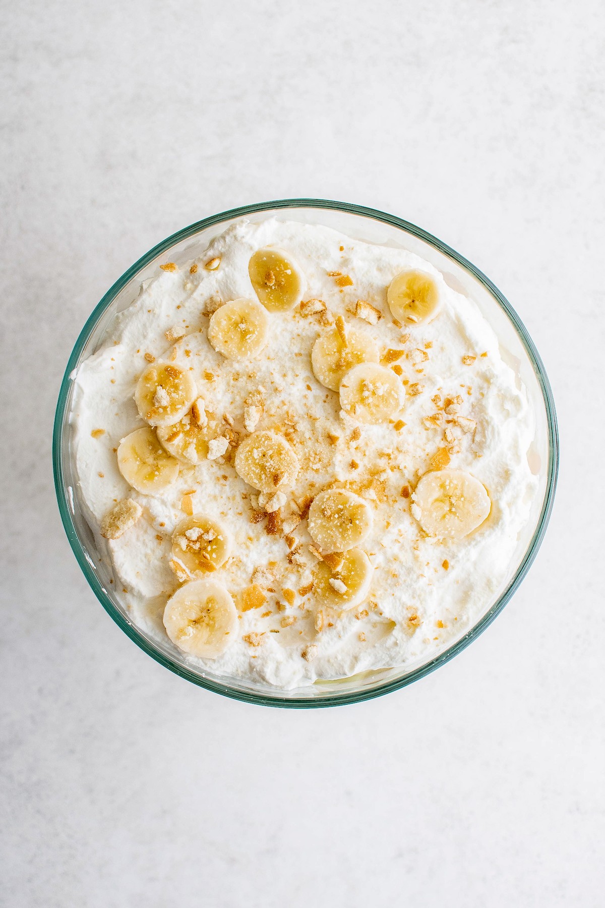 A dessert topped with sliced bananas, whipped cream, and cookie crumbs.
