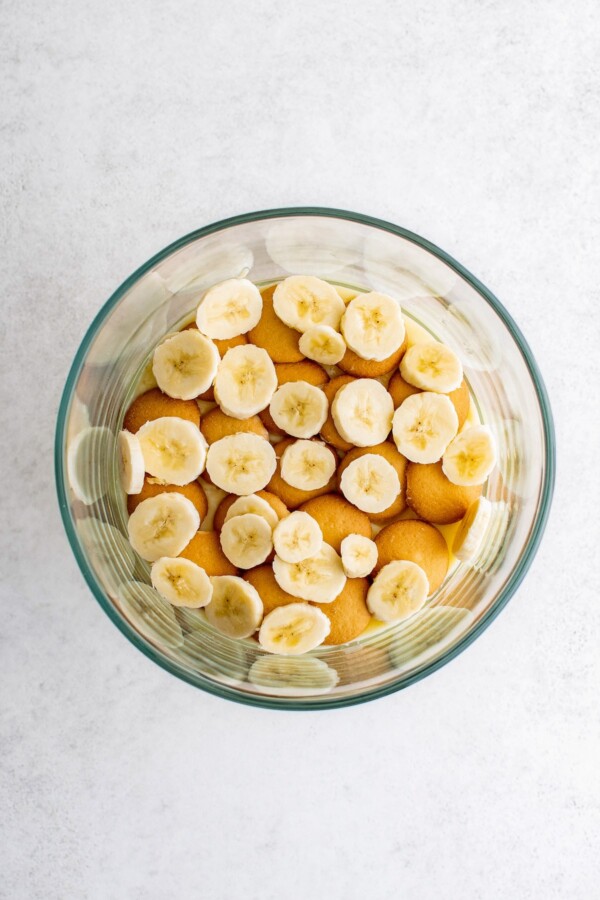 Banana slices scattered over cookies in a trifle dish.