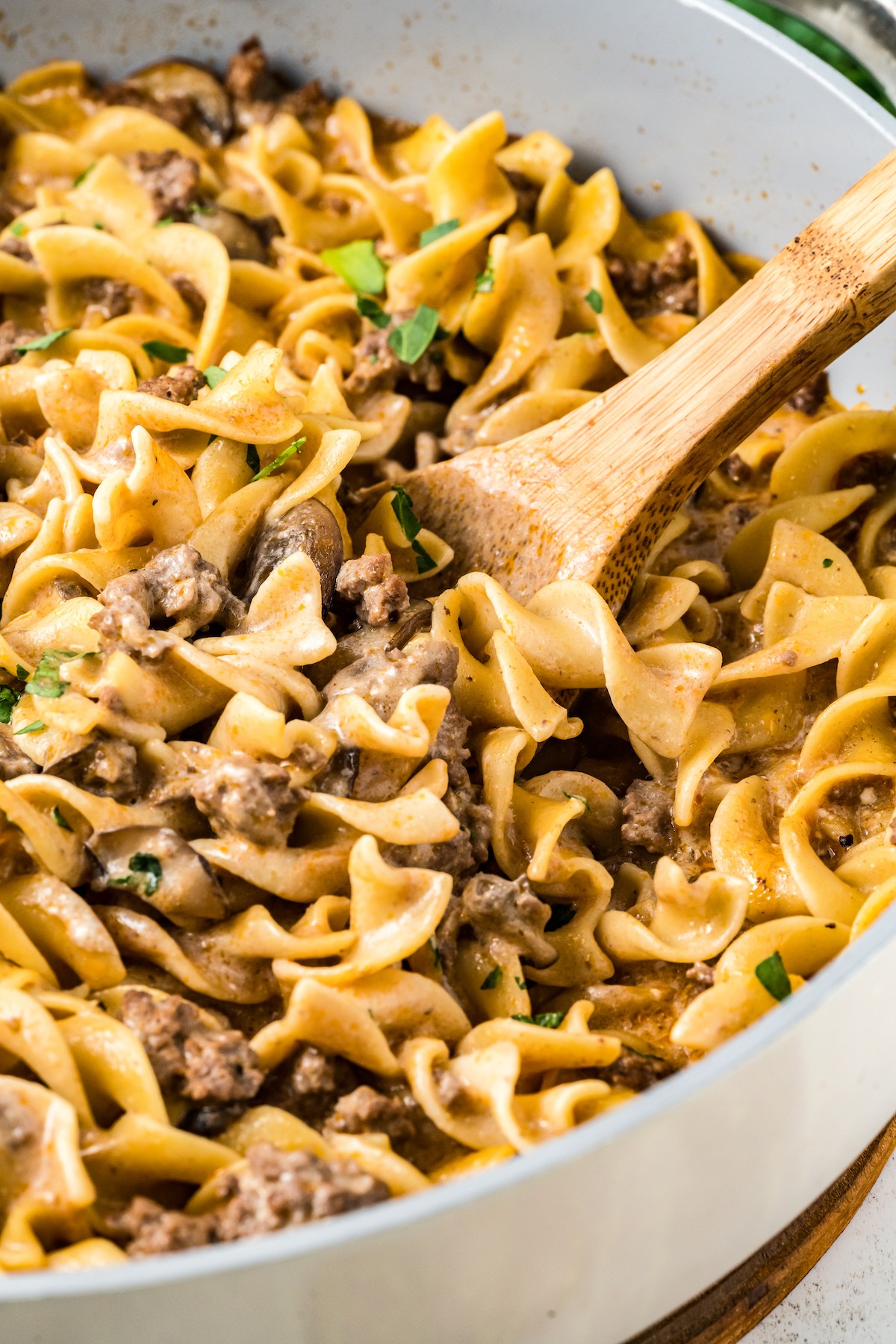 Ground beef stroganoff in a pot with a wooden spoon resting in it.