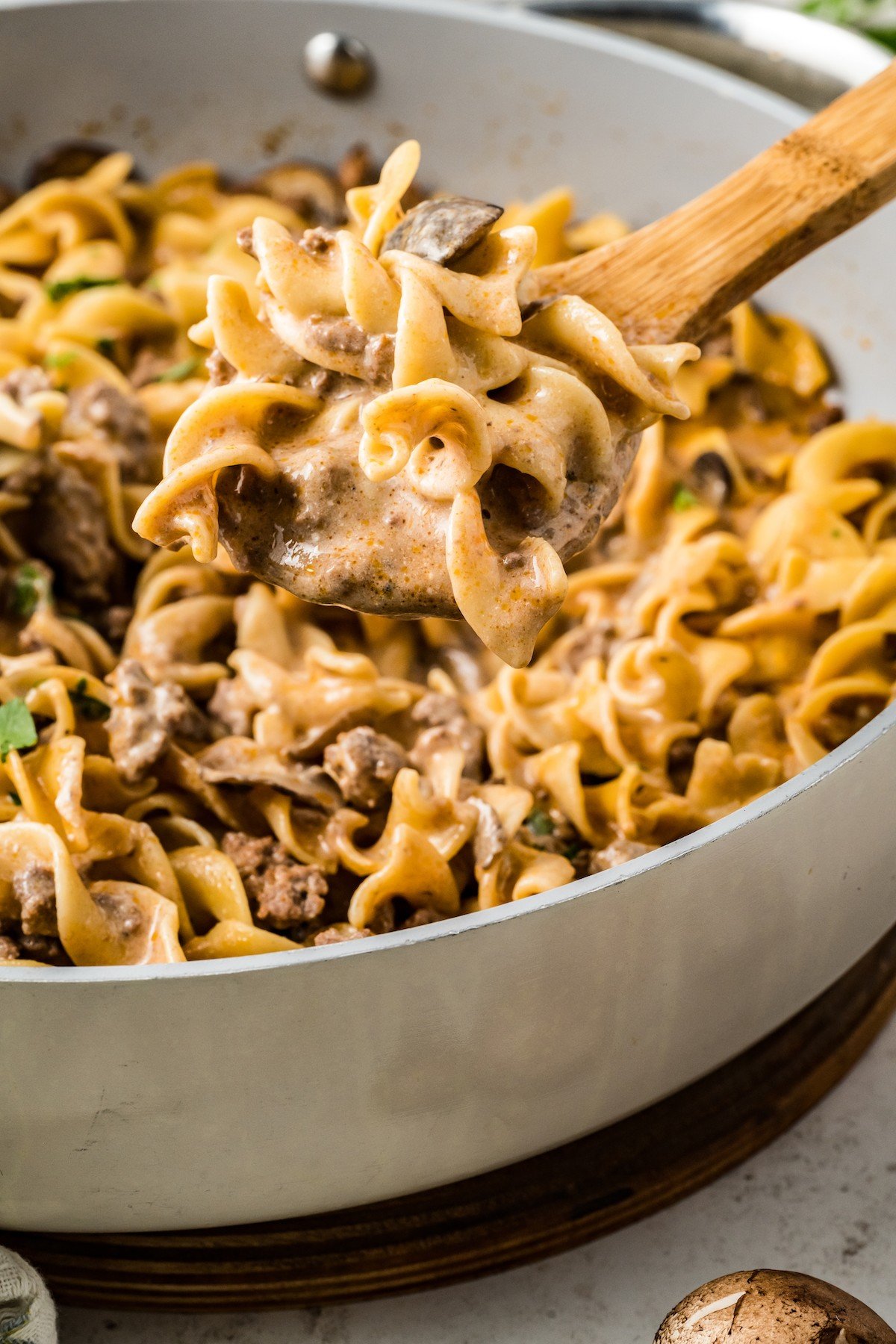 Lifting a spoonful of homemade hamburger helper out of a skillet.