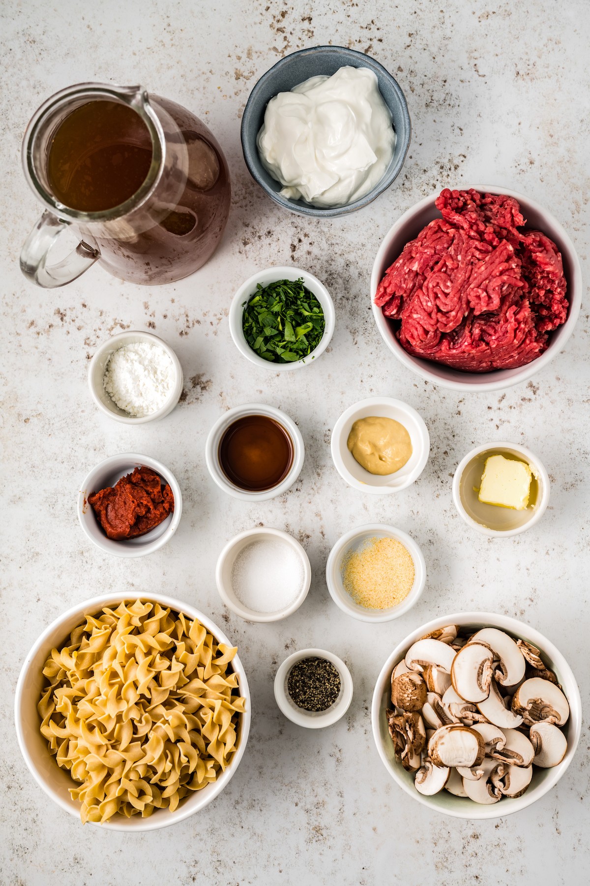 From top: Beef broth, sour cream, ground beef, cornstarch, parsley, tomato paste, worcestershire sauce, mustard, butter, salt, garlic powder, egg noodles, pepper, mushrooms.