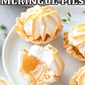 Bite size lemon meringue pies on a tray with a bite taken out of one pie.