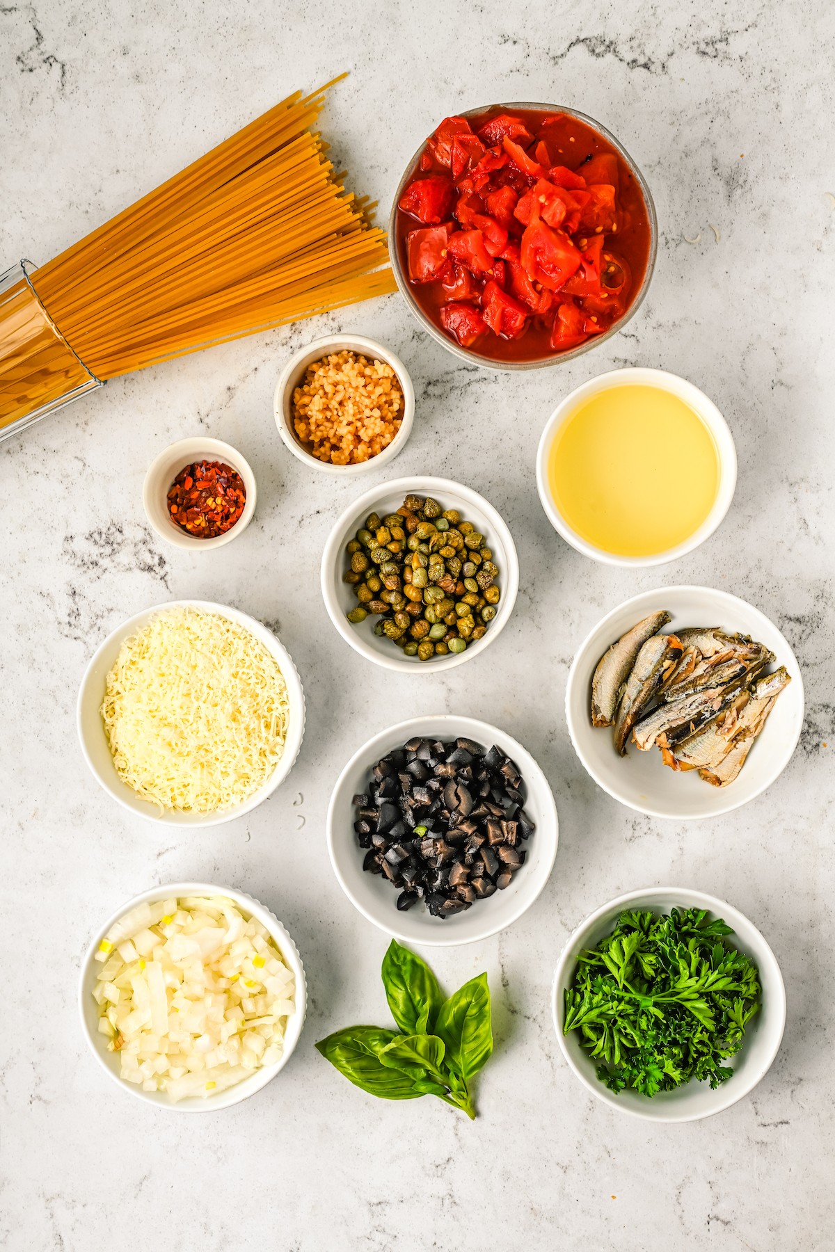 The ingredients for spaghetti puttanesca, measured and arranged on a work surface.
