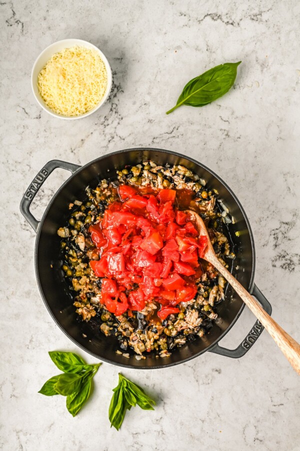 Adding diced tomatoes in a skillet.