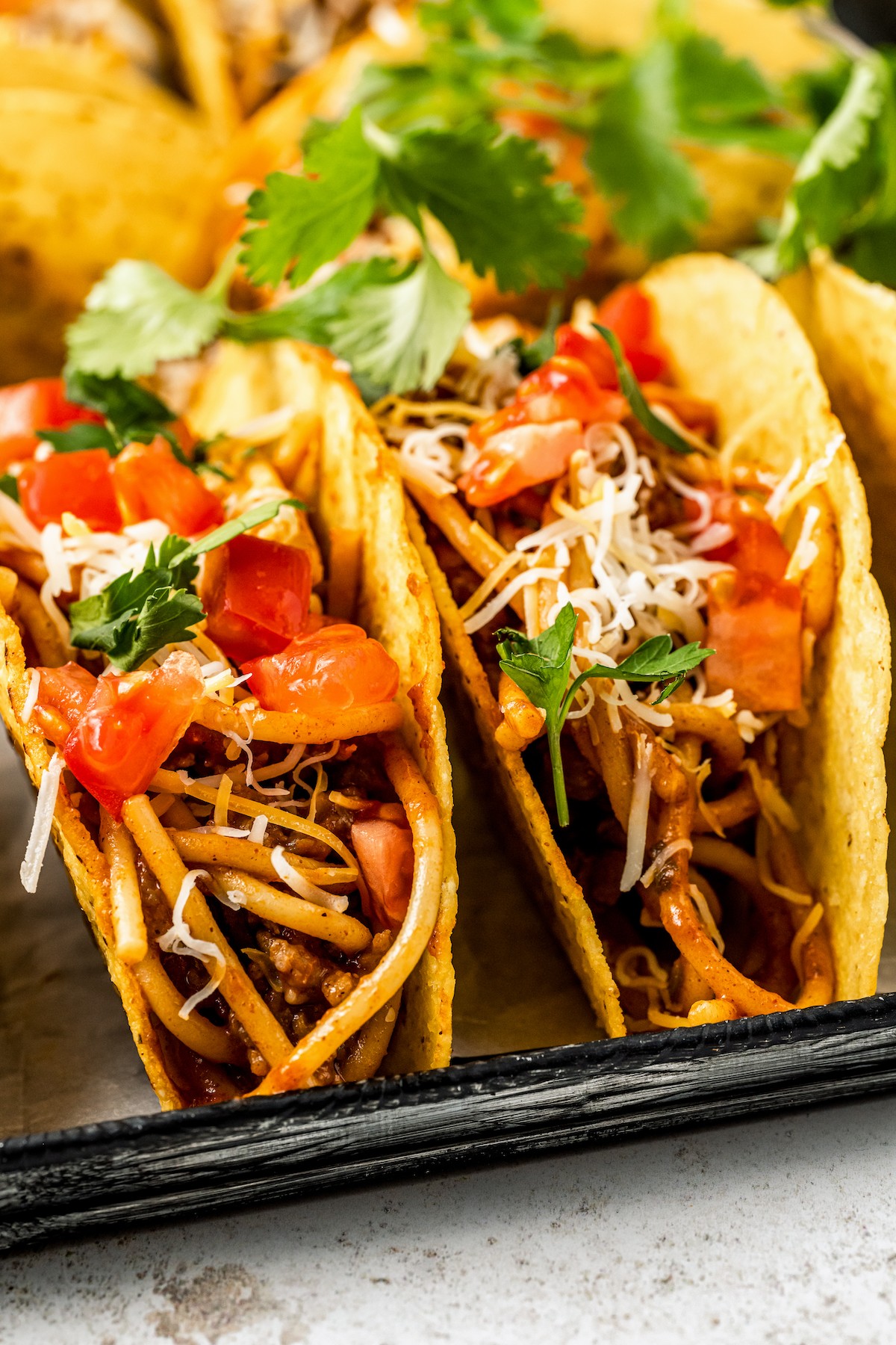 Close-up shot of tacos with spaghetti inside.