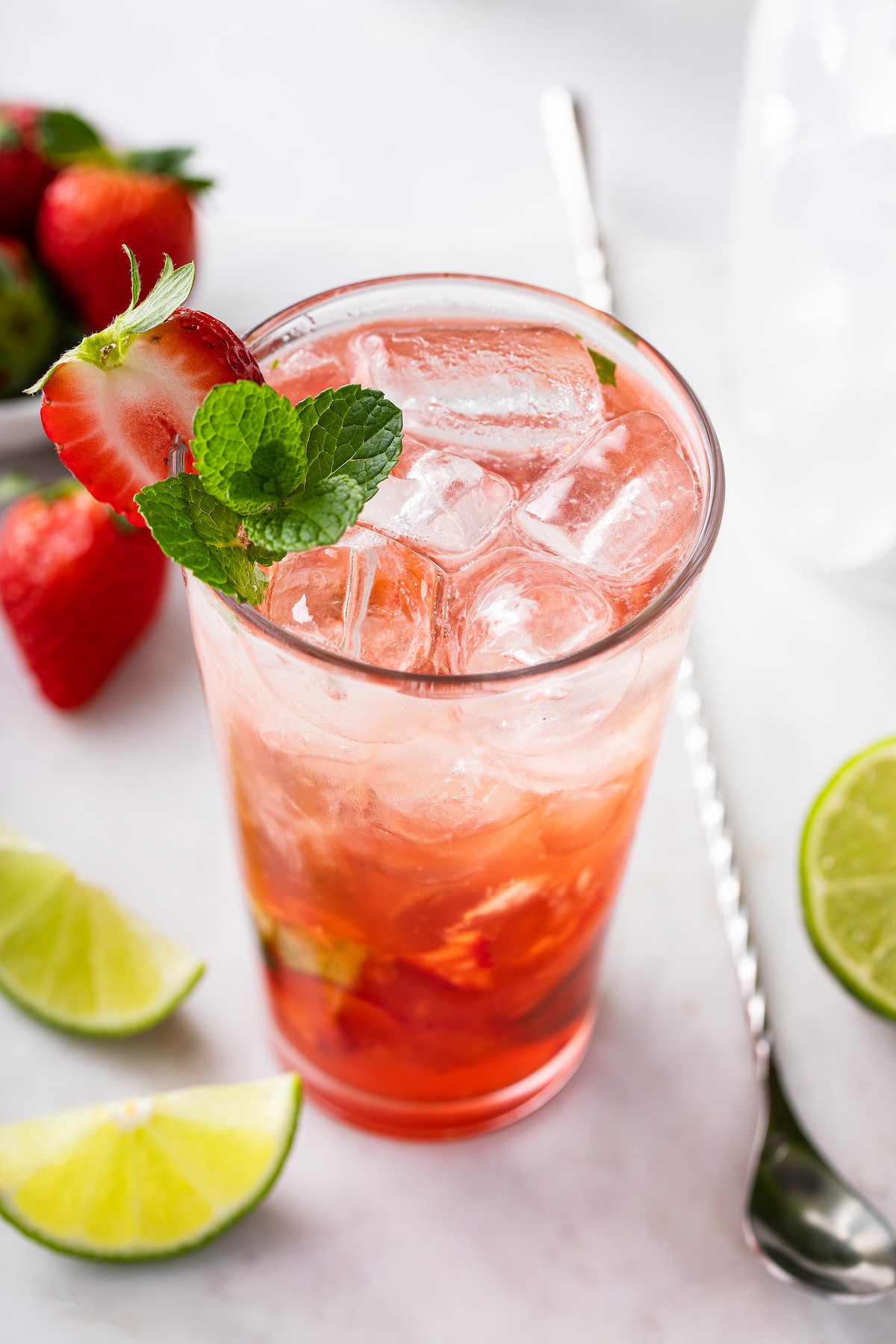 A cocktail garnished with fresh mint and strawberry.