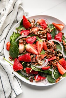 A strawberry salad with fresh spinach and pecans.