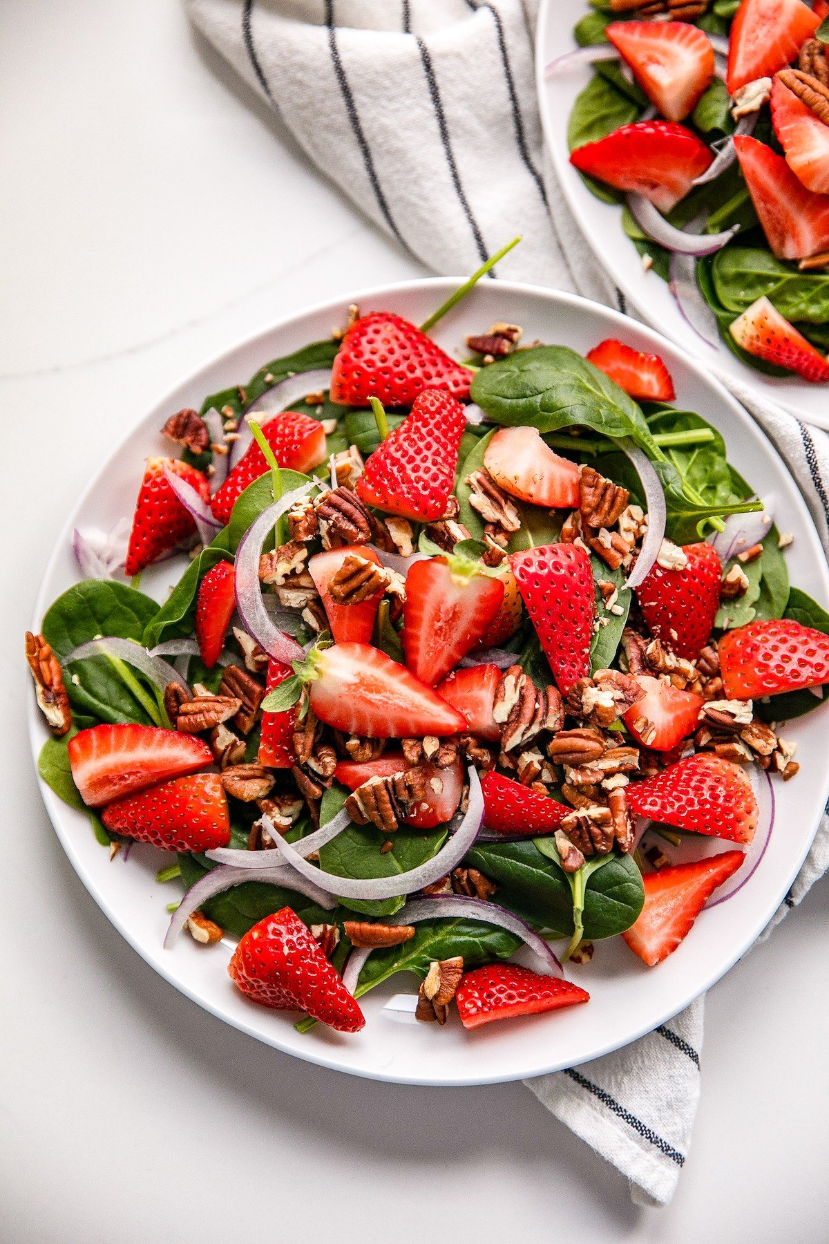 Spinach strawberry salad in a white bowl.