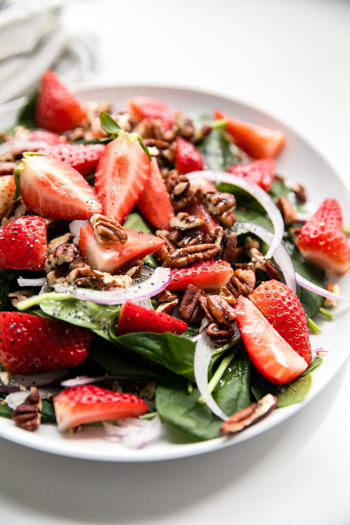Salad with strawberries, onions, spinach, and pecans.