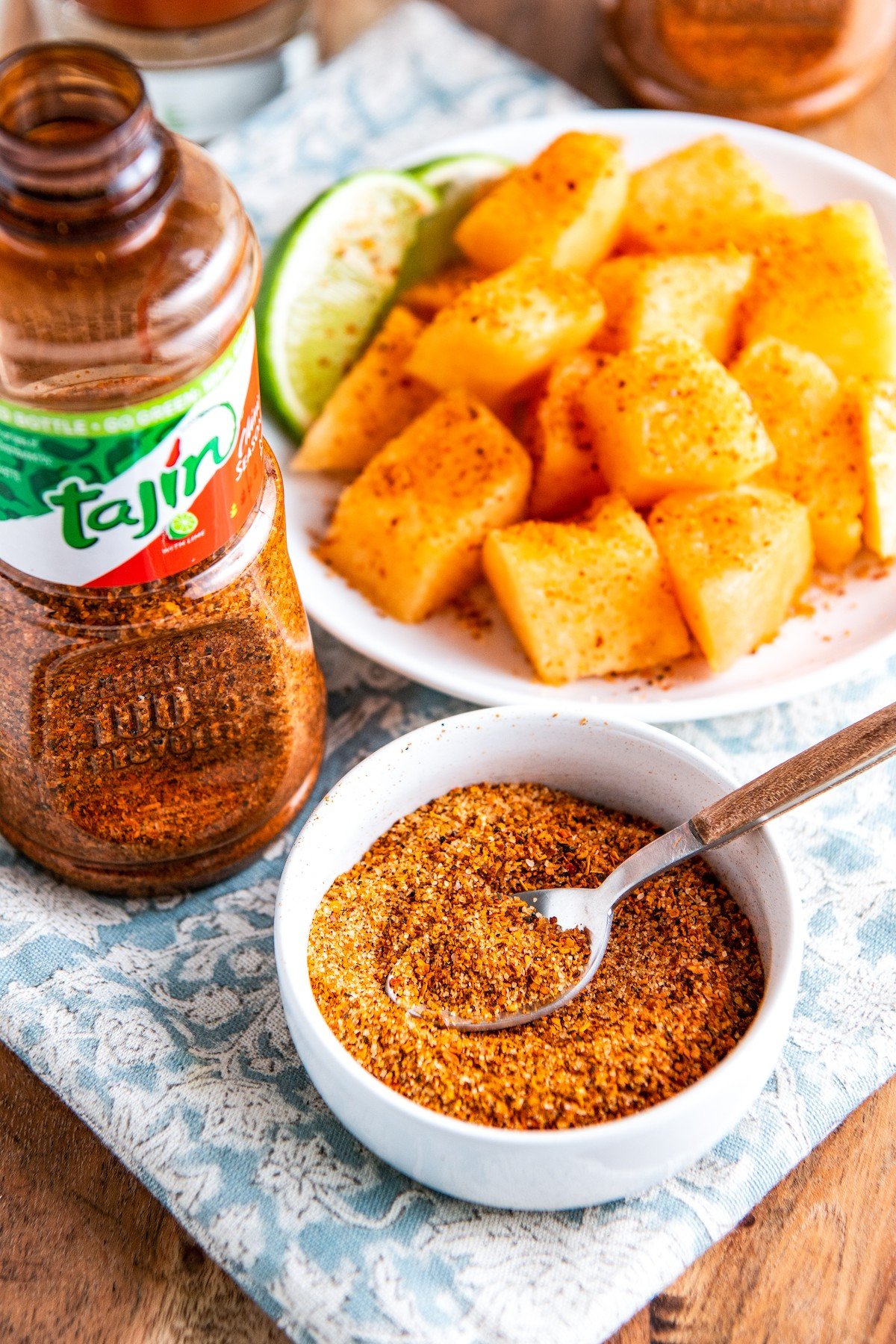 Tajin in a bowl with a spoon and sprinkled on top of mango.