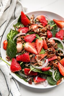 A strawberry salad with fresh spinach and pecans.