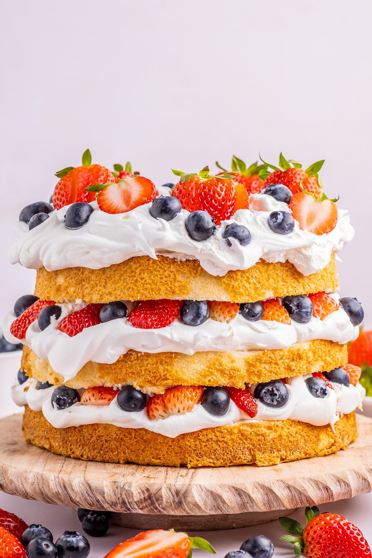 A layered red-white-and-blue cake with whipped cream and berries.