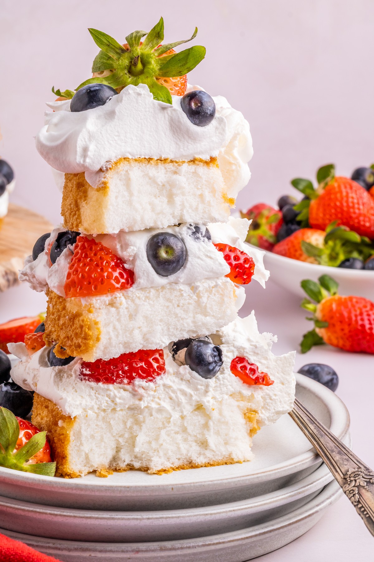 A tall, stacked dessert with whipped cream, berries, and cake.