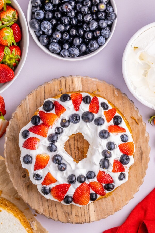 Strawberries and blueberries arranged on a Cool-whip covered layer of cake.