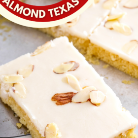 A white texas sheet cake on a baking tray cut into squares.