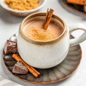 A mug filled with Chocolate Atole with a cinnamon stick.