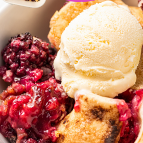 Ice cream on top of a bowl of berry cobbler.