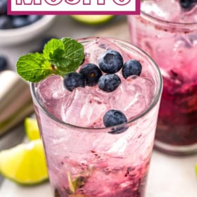 Blueberry Mojito in a glass with fresh blueberries and mint on top.