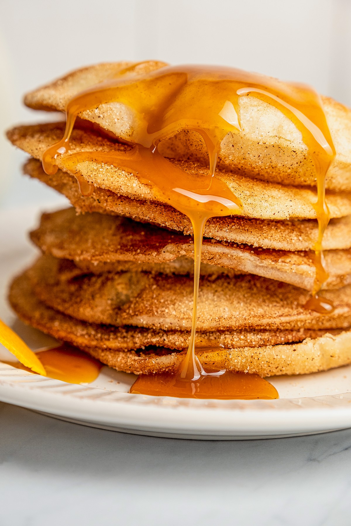 Caramel drizzled on top of a stack of buñuelos on a plate.
