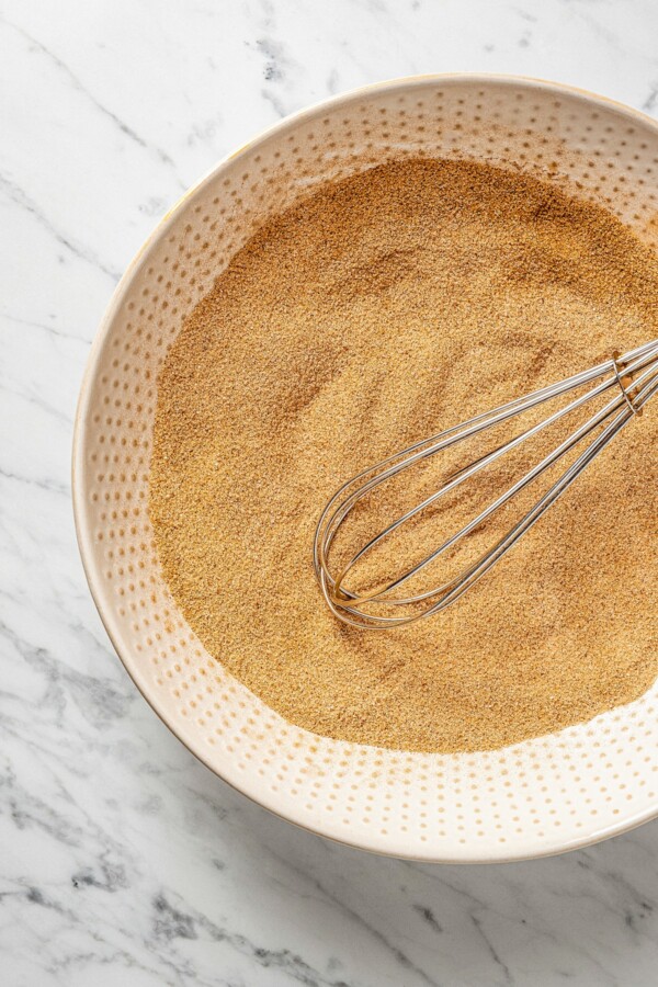 Orange scented cinnamon sugar in a bowl with a whisk stirring it.