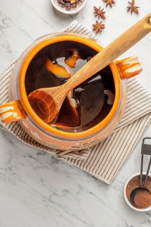 A pot of Café de Olla being stirred with a wooden spoon.