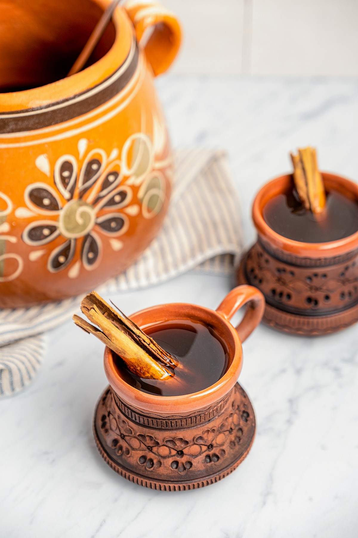 Two cups and a pot filled with Café de Olla (Cinnamon Mexican Coffee). 